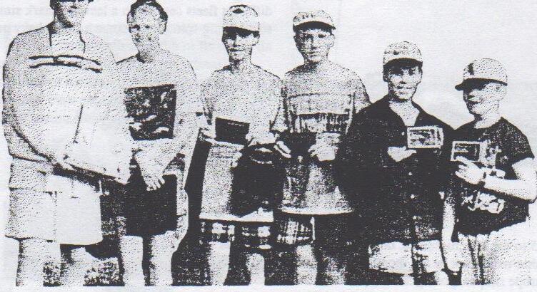 Six junior sailors in caps standing in a row holding trophies and plaques