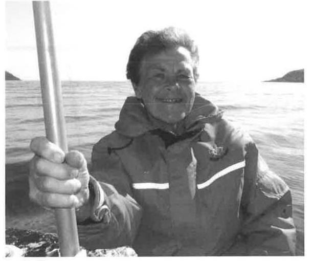 Commodore Teresa Miolla holding a paddle aboard a boat on the water