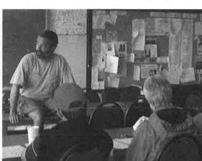 Workshop participants seated for an indoor land session, with an instructor addressing the group