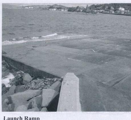 A concrete boat launch ramp at Largs Sailing Club, with rocky breakwater on the left