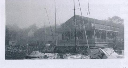 The Shelburne Harbour Yacht Club clubhouse in the fog, with several boats moored in front