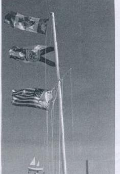 Signal flags flying from a flagpole at the yacht club, including a Canadian and American flag