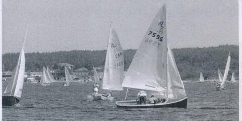 Two Albacores racing, sail number 7596 in the foreground, with more boats and spectators on shore behind
