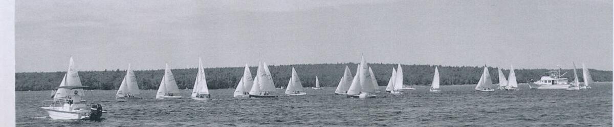 A wide panorama of the full Albacore fleet racing under sail off Shelburne, with the committee boat in the foreground