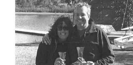 Ralph Glass and Cathyann White, arms around each other, holding two trophy glasses