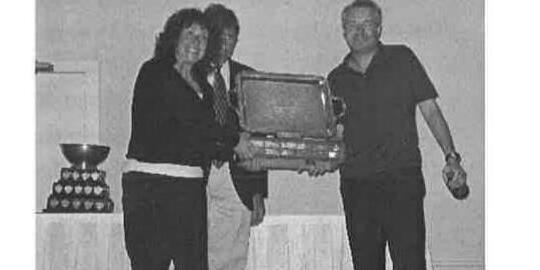 Ralph Glass and Cathyann White receiving a large trophy from a presenter