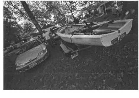 A car towing an Albacore trailer, parked on a residential street under trees