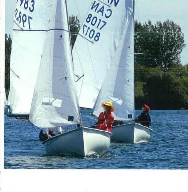 Two Albacores racing near shore, crew in bright yellow and red gear