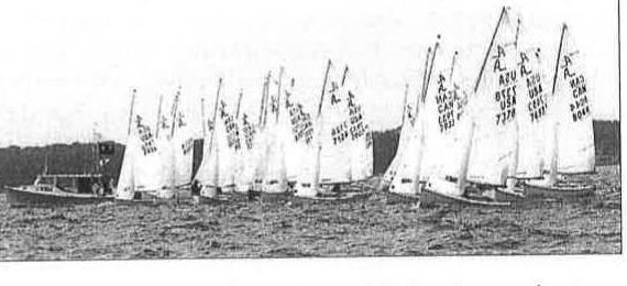 A fleet of Albacores starting a race, with the race committee boat in the foreground