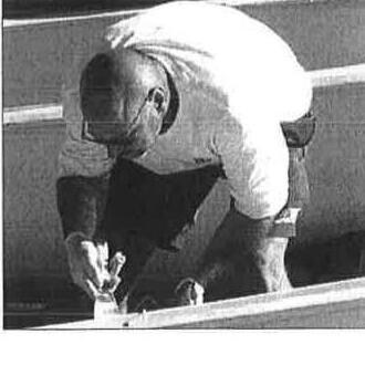 A person applying epoxy or fiberglass along the gunwale of a boat