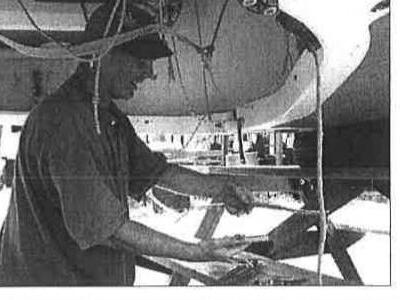 A person handling battens and the mainsail while working on a boat