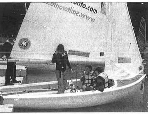 An Albacore rigged indoors on a small lake at the Toronto Boat Show, with a crew of three aboard