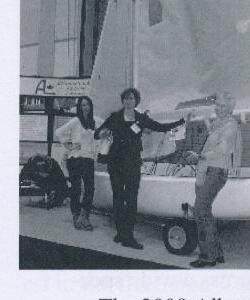 Three people touring the Ontario Yachts factory floor, with an Albacore hull dolly nearby