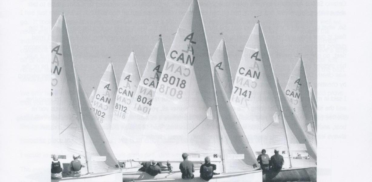 A fleet of Albacores sailing with several crew standing on a dock in the foreground