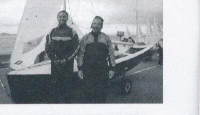 Two men standing beside a trailered Albacore at a dockside