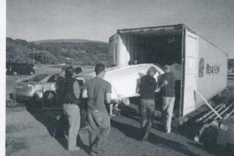 A group loading an Albacore hull into a shipping container truck