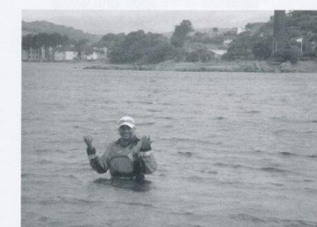 A sailor standing chest-deep in the water after a capsize
