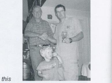 Guy Tipton shaking hands with another man indoors while a young boy looks on