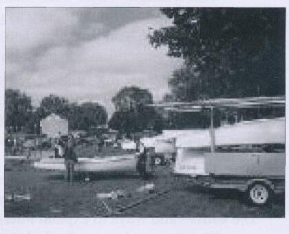 Albacores being stored for winter in a grassy yard, one upright on a trailer under a partial cover