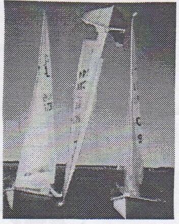 Photo of an Albacore apparently flipped vertically on top of other boats, sails pointing sideways