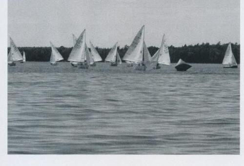 A fleet of Albacores racing with a coloured mark buoy in the foreground