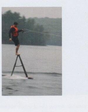 A man riding a hydrofoil water-ski board being towed behind a boat