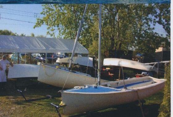 Two Albacore hulls on trailers parked on grass beside a tent