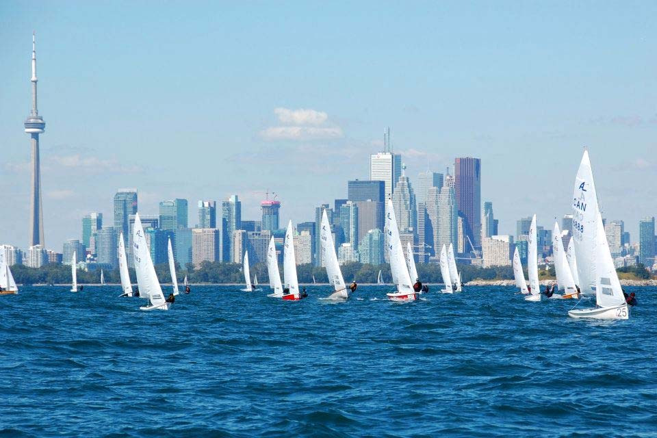 A fleet of Albacores sailing on Lake Ontario in front of the Toronto skyline and CN Tower