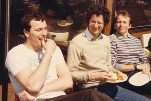 Peter Vasoff and two friends seated together, smiling, at an outdoor table