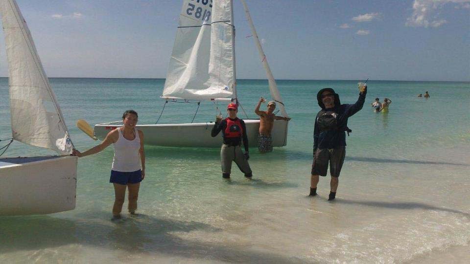 A group of sailors celebrating on a Sarasota beach with their Albacores