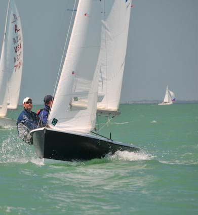 A crew hiking out on an Albacore mid-fleet, sailing hard upwind