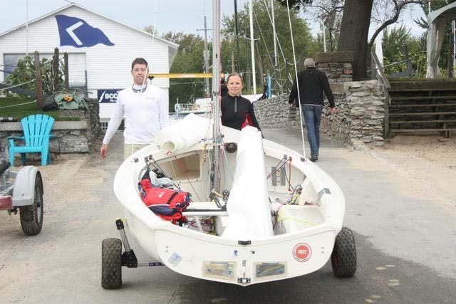 Jefferson and Tracy Hall walking their Albacore on its trailer down a launch ramp beside a yacht club