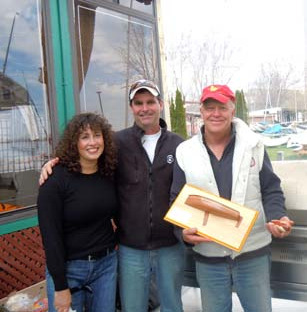 Three CAA members posing together, one holding a wooden half-model award