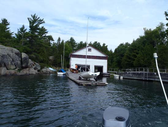 A white boathouse on a rocky Georgian Bay shoreline, with an Albacore docked alongside