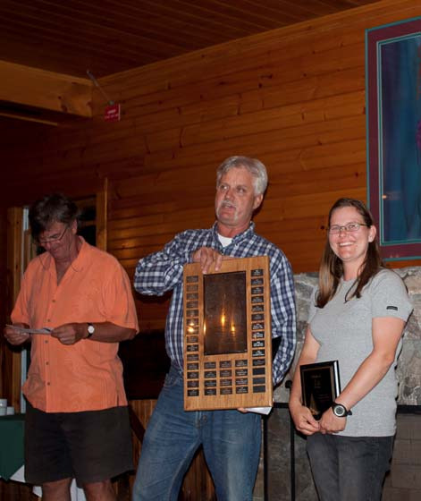 Three people at the awards dinner, a man holding a wooden plaque award