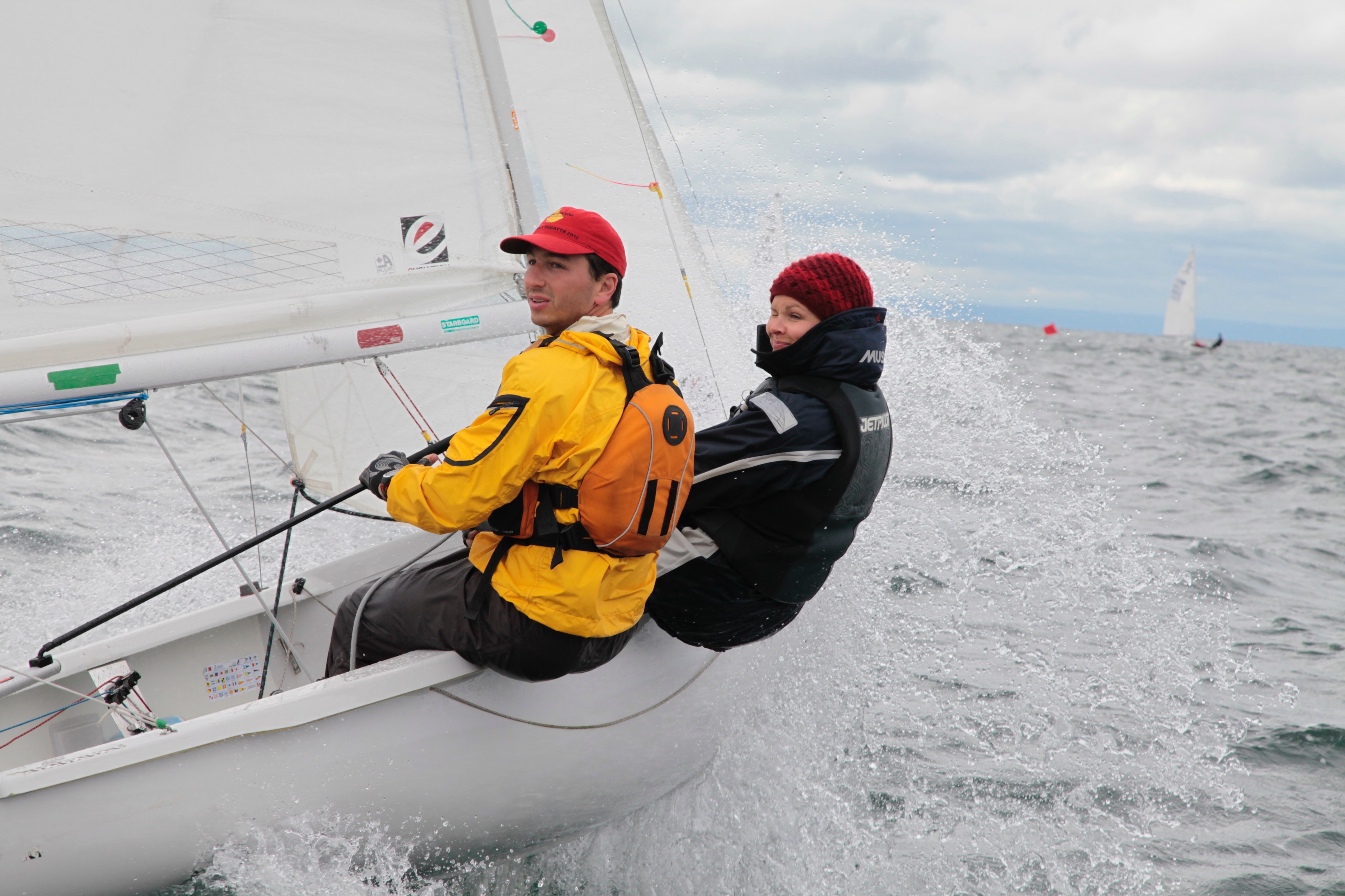 Two sailors hiking hard through spray on an Albacore
