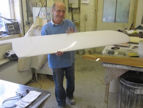 Phil Milanes holding a newly moulded white centerboard in his workshop