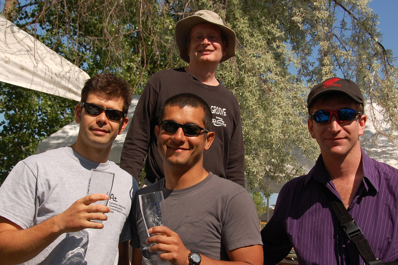 Four sailors holding trophy glasses, smiling for the camera