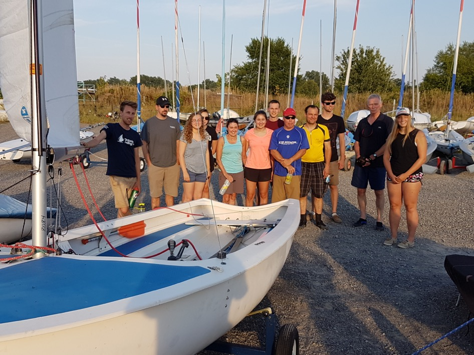 A group of new sailors gathered around a rigged Albacore in the boatyard at Nepean Sailing Club