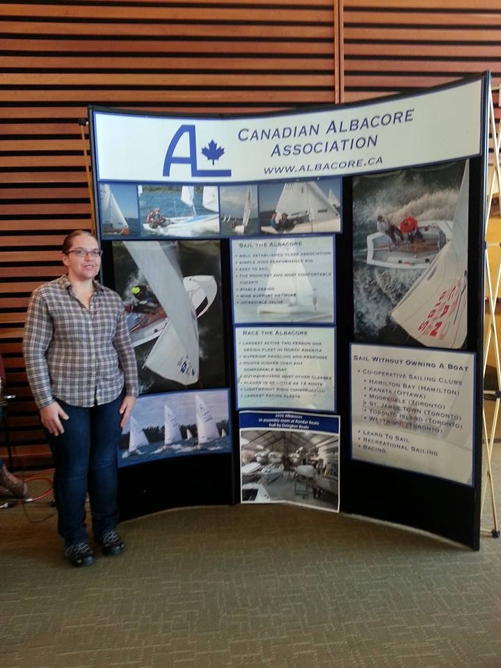 A volunteer standing beside the CAA display board at the Toronto Reference Library