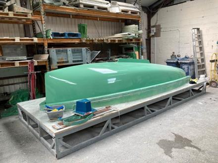 A green Rondar Albacore hull on a workshop stand