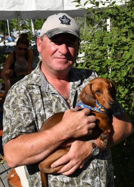 A CAA volunteer holding a small dog at a regatta