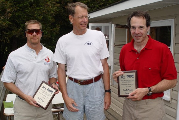 Peter Duncan receiving a sailing service award, flanked by two other men