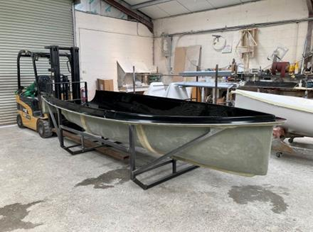 A black Rondar Albacore hull being moved by forklift in the workshop