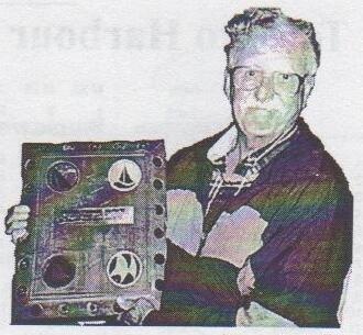 Jake Smythe holding up the Spanish Donkey trophy, a plaque mounted with two sailboat emblems
