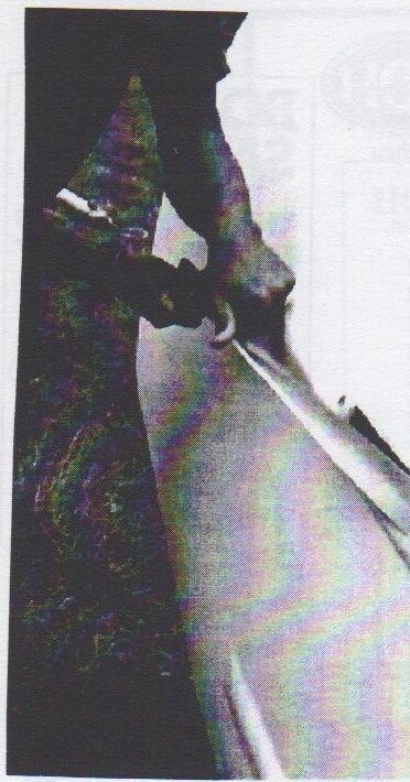 Close-up of hands working a long strip of material along the edge of a centreboard slot