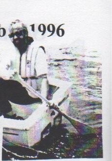 A sailor in a life jacket paddling an Albacore