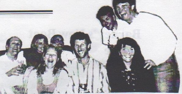 A laughing group of Canadian and American sailors crowded together at a party