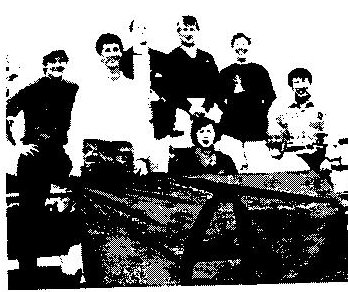 Group photo of the Canadian sailors and friends gathered around a boat on shore