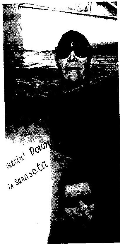 A sailor in dark sunglasses swimming in the water, captioned by hand “Gettin’ Down in Sarasota”